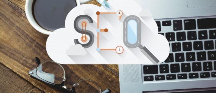 The word "SEO" is seen in a cloud icon hovering above a laptop on a desk.